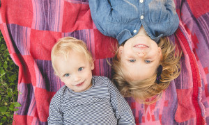 two blonde sisters laying on colorful blanket unique perspective