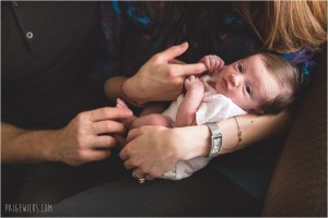 newborn looks eagerly on holding mothers finger