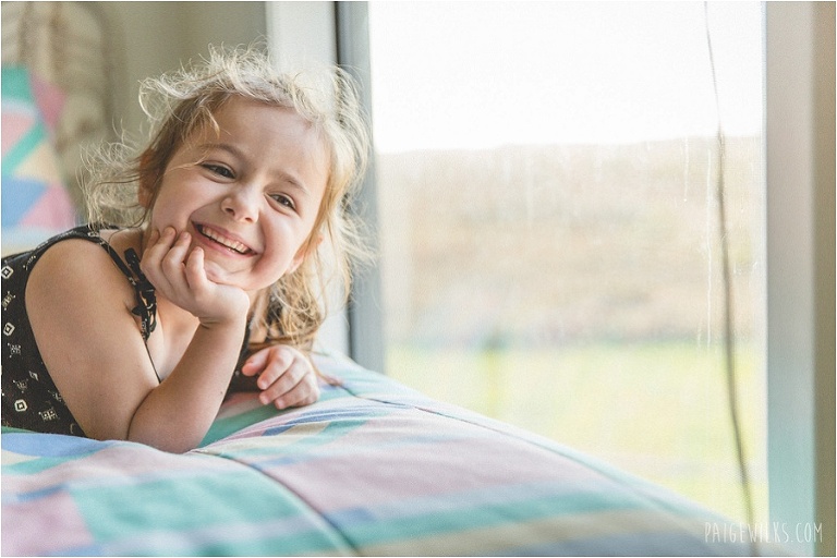 little girl smiling towards window beach house