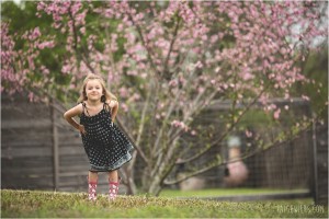 little girl in front of blooming pink peach tree flowers