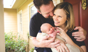 father kisses new mother newborn photography